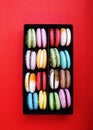 Tasty different colored macarons in black box on red background Royalty Free Stock Photo