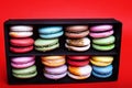 Tasty different colored macarons in black box on red background Royalty Free Stock Photo