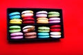 Tasty different colored macarons in black box on red background. Royalty Free Stock Photo