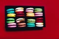 Tasty different colored macarons in black box on red background. Royalty Free Stock Photo