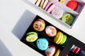 Tasty different colored macarons in white and black boxes on light background Royalty Free Stock Photo