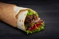 Tasty doner kebabs with fresh salad trimmings and shaved roasted meat served in tortilla wraps on brown paper as a