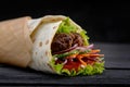 Tasty doner kebabs with fresh salad trimmings and shaved roasted meat served in tortilla wraps on brown paper as a