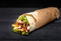 Tasty doner kebabs with fresh salad trimmings and shaved roasted meat served in tortilla wraps on brown paper as a