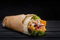 Tasty doner kebabs with fresh salad trimmings and shaved roasted meat served in tortilla wraps on brown paper as a