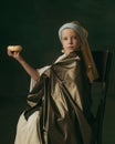 Medieval little girl as a lady with a pearl earring on dark studio background. Concept of comparison of eras, childhood
