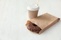 Tasty donut in paper bag and coffee on wooden table Royalty Free Stock Photo