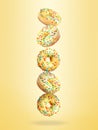 Tasty donuts with sprinkles falling on pastel golden background