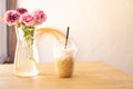 Tasty drinking, cup of ice cappuccino coffee decorated with white milk froth in a tall plastic glass on brown wooden table