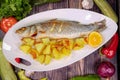 Tasty European bass with sauteed potatoes on a plate on a wooden table