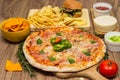 Tasty fast food on table. Pepperoni pizza and pizza Capricciosa , hamburger and potato chips Royalty Free Stock Photo