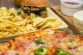 Tasty fast food on table. Pepperoni pizza and pizza Capricciosa , hamburger and potato chips Royalty Free Stock Photo