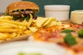 Tasty fast food on table. Pepperoni pizza and pizza Capricciosa , hamburger and potato chips Royalty Free Stock Photo