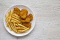 Tasty Fastfood: Chicken Nuggets and French Fries on a plate on a white wooden background, top view. Overhead, from above, flat lay