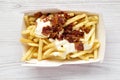 Tasty fastfood: french fries with cheese sauce and bacon in a paper box, overhead view. Flat lay, from above, top view Royalty Free Stock Photo