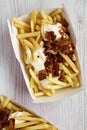 Tasty fastfood: french fries with cheese sauce and bacon in a paper box, view from above. Flat lay, top view Royalty Free Stock Photo