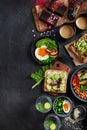 Tasty food with avocado toast, vegetables, eggs on dark background. Helthy breakfast concept