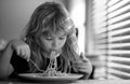 Tasty food, messy child eating spaghetti Happy child boy with spoon eats itself. Kid eating food on kitchen. Close up Royalty Free Stock Photo