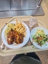 A food tray that includes chicken, chips, rice and salad