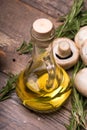 Tasty, fragrant sunflower oil for salads on a wooden background. A few branches of rosemary and mushrooms on a desk.