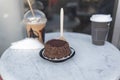 Frappuccino, small chocolate cake, and coffee cup on round gray table