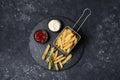 Tasty French fries, ketchup, rosemary and mayonnaise on black textured table, top view Royalty Free Stock Photo