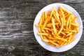 Tasty french fries on plate, on wooden table background