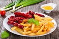 Tasty french fries and sausages on plate, close-up