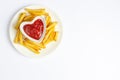 Tasty french fries on white plate with heart pattern of ketchup