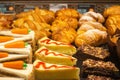 Tasty fresh cakes in showcase. Bakery in cafeteria. Baked croissants, carrot and chocolat cake. Pastry closeup. Royalty Free Stock Photo