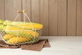 Tasty fresh corn cobs in metal basket on white wooden table, space for text Royalty Free Stock Photo