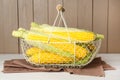 Tasty fresh corn cobs in metal basket on white wooden table Royalty Free Stock Photo