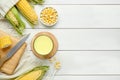 Tasty fresh corn milk in glass and cobs on white wooden table, flat lay. Space for text Royalty Free Stock Photo