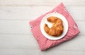 tasty Fresh crispy croissants arranged in white plate on cloth . Flat lay composition food photography.