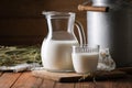Tasty fresh milk in can, jug and glass on wooden table. Space for text Royalty Free Stock Photo