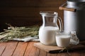 Tasty fresh milk in can, jug and glass on wooden table. Space for text Royalty Free Stock Photo