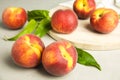 Tasty fresh peaches, leaves and stone board on table Royalty Free Stock Photo