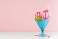 Tasty fresh pink ice cream in blue bowl with strawberry sauce, silver spoon, green mint on white wooden table and soft light.