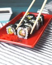 Tasty and fresh sushi set served in a red plate with wooden chopsticks. Close-up, selective focus on sushi. Royalty Free Stock Photo