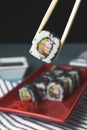 Tasty and fresh sushi set served in a red plate with wooden chopsticks. Close-up, selective focus on sushi. Royalty Free Stock Photo