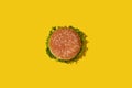 Tasty fresh unhealthy hamburger with ketchup and vegetables on yellow vibrant bright background. Top View with Copy