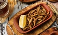 Tasty fried anchovies in cornmeal with lemon piece in wooden background, grilled small fish for beer, snacks