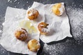 Tasty fried dough balls with cheese and powdered sugar on the baking paper, grey rustic surface