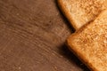 Tasty fried toast bread slices lie on a natural brown wooden background.