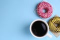 Tasty frosted donuts and cup of coffee on light blue background, flat lay. Space for text