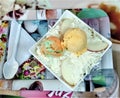 Tasty fruit salad with cheese, ice cream and milk cream, on its square plate, its respective spoon and napkin.