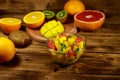 Tasty fruit salad in glass bowl and fresh fruits on wooden table Royalty Free Stock Photo