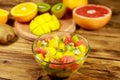 Tasty fruit salad in glass bowl and fresh fruits on the wooden table Royalty Free Stock Photo