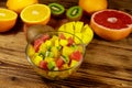 Tasty fruit salad in glass bowl and fresh fruits on the wooden table Royalty Free Stock Photo