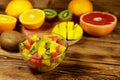 Tasty fruit salad in glass bowl and fresh fruits on  a wooden table Royalty Free Stock Photo